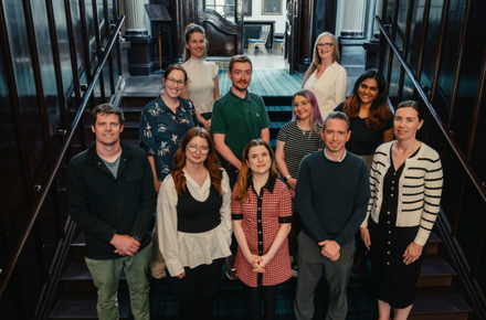 Group of colleagues smiling on the College stairs